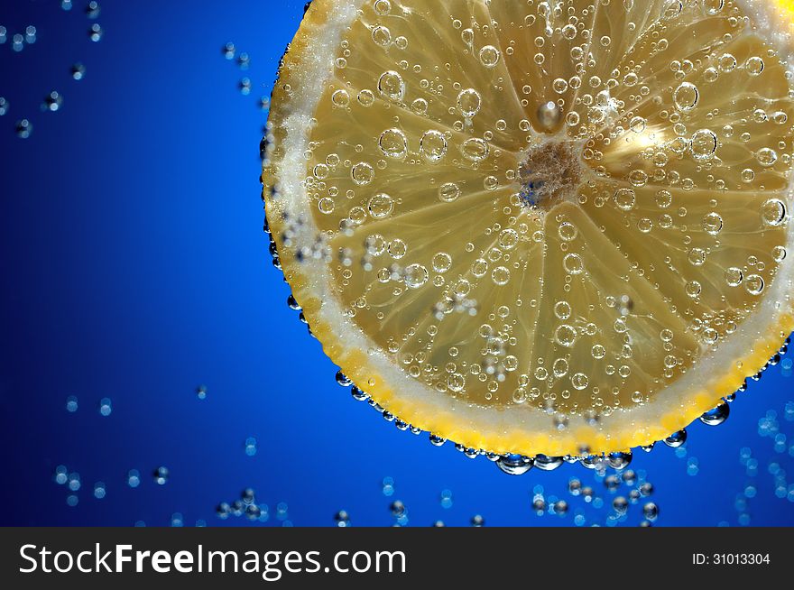 Slice of fresh lemon in water with air bubbles