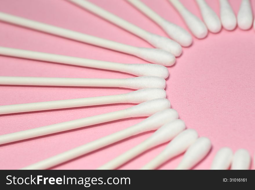 Cotton swabs which were displayed to draw a circle on a pink background