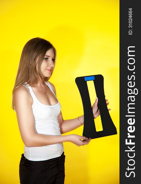 Pretty girl posing with a sports trainer on yellow background
