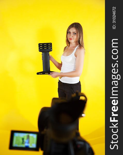 Young woman posing with a sports trainer on yellow background
