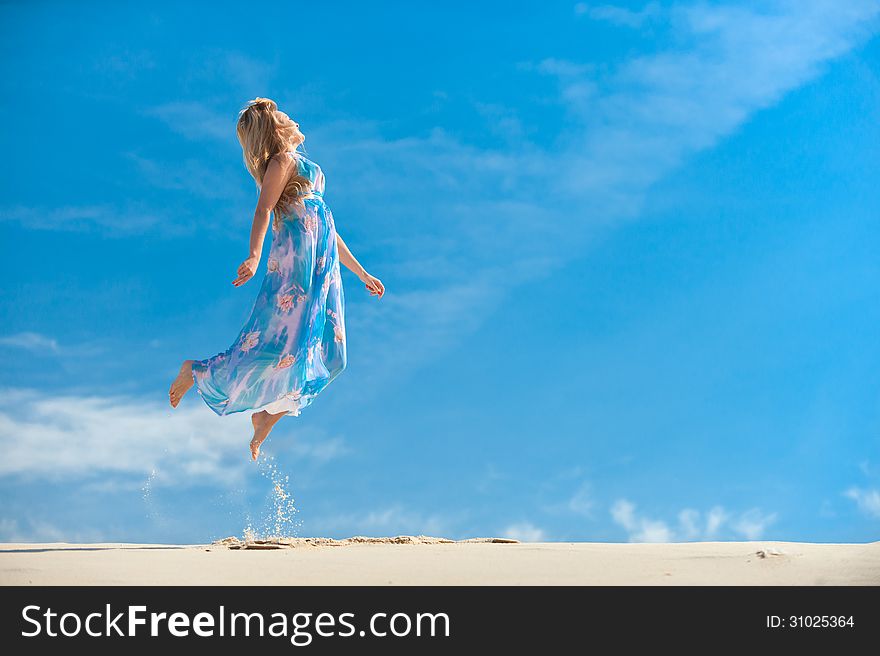 Young woman high jumps on the background of blue sky