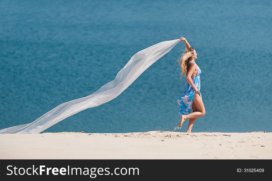 Woman running along the sand, holding a white cloth. Woman running along the sand, holding a white cloth