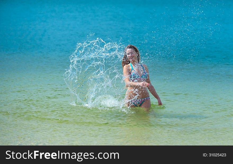 Young woman beating the water with his hands and makes a splash. Young woman beating the water with his hands and makes a splash