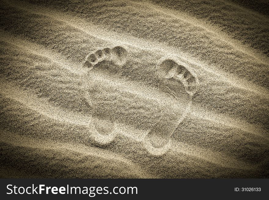 Two footprints in sand on the desert beach