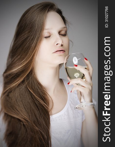 Portrait of lovely woman with gorgeous long straight hair, beautiful fresh face and shut eyes, smelling a glass of drink while holding it in her hand with red manicure nails. Isolated over grey background. Portrait of lovely woman with gorgeous long straight hair, beautiful fresh face and shut eyes, smelling a glass of drink while holding it in her hand with red manicure nails. Isolated over grey background.