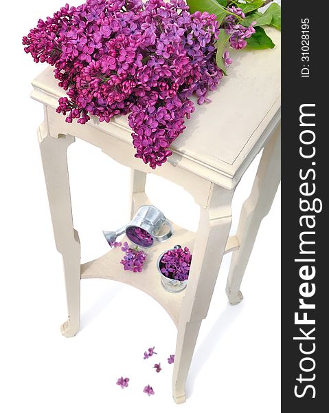 Bunch of lilas on a little table with petals on white background. Bunch of lilas on a little table with petals on white background