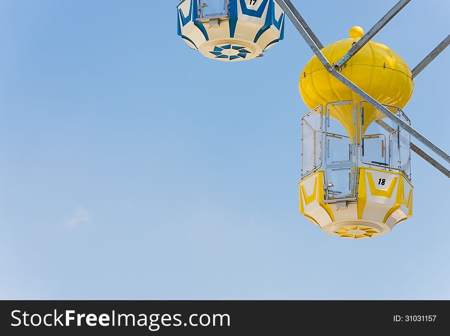 Yellow capsule seat of carousel in amusement park with clear blue sky