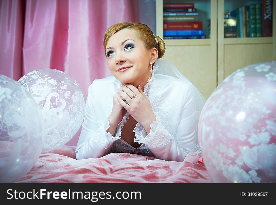 Happy bride with pink ballons on bed