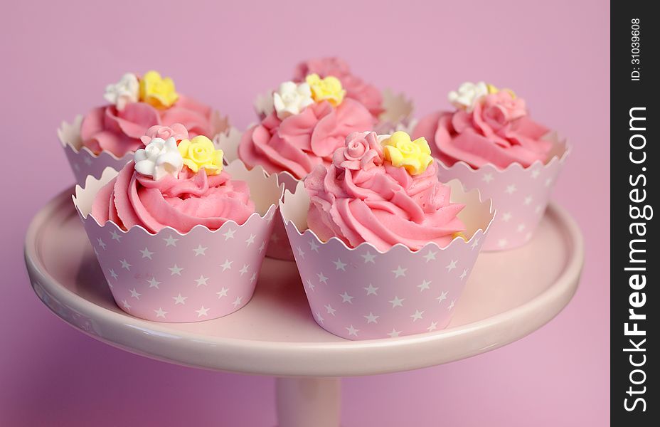 Beautiful pink decorated cupcakes on pink cake stand in star cups.
