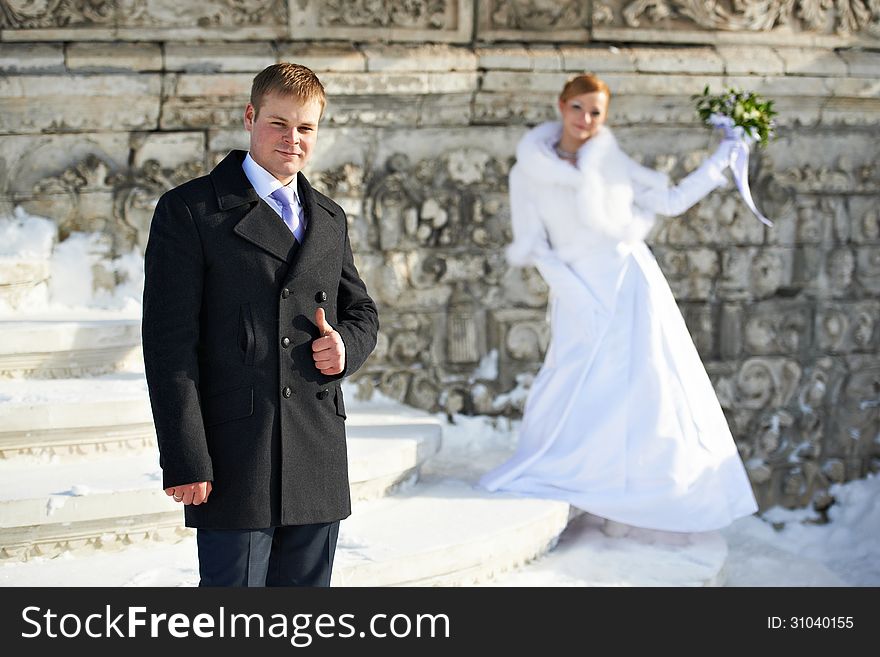 Happy bride and groom on wedding walk near stone wall background