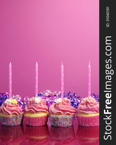 Pink birthday cupcakes with polka dot candles against a pink background. Vertical with copy space. Pink birthday cupcakes with polka dot candles against a pink background. Vertical with copy space.