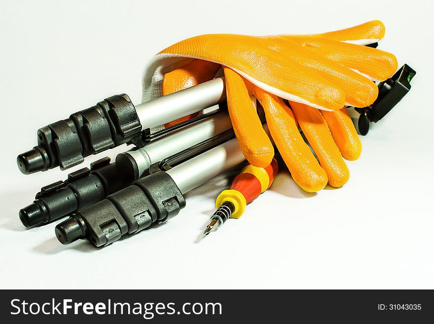 Gloves and tripod with screwdriver on white background.