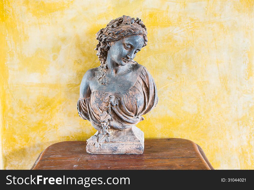 Bust of a beautiful lady on the table in front of yellow wall. Bust of a beautiful lady on the table in front of yellow wall.