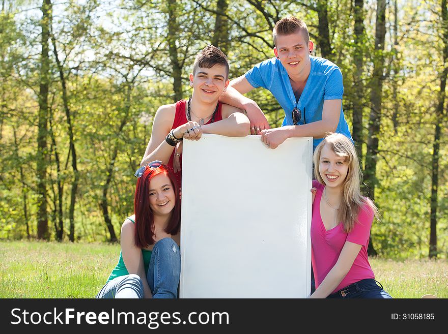 Four teenagers in colored shirts and a white board which can be used for your advertisements. Four teenagers in colored shirts and a white board which can be used for your advertisements