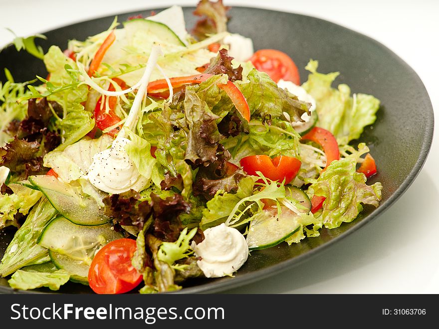 Healthy green salad on the black plate