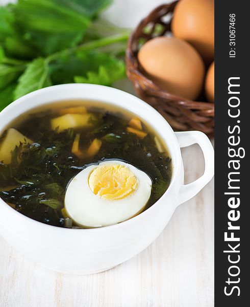 Nettle soup with egg in the white plate