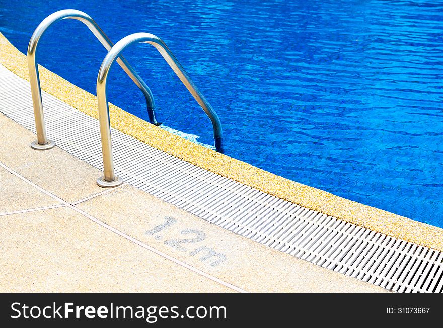 Grab bars ladder in the blue swimming pool