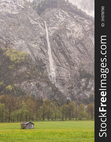 Beauty landscape. Wooden cottage in background big mountain and waterfall - France. Beauty landscape. Wooden cottage in background big mountain and waterfall - France.