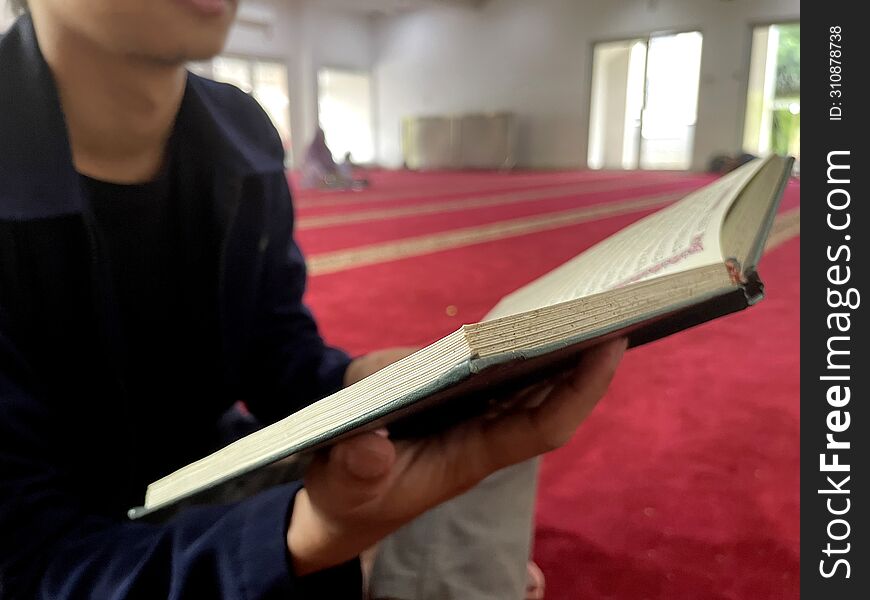 Read the Islamic holy book Al-Quran. holding the Koran in open position