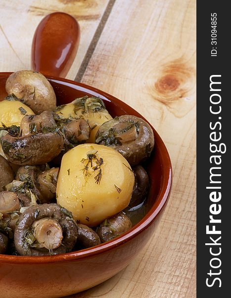 Delicious Stew with Champignon Mushrooms, Roasted Potato, Dill, Parsley, Leek and Onion in Brown Frying Pan closeup on Wooden background. Delicious Stew with Champignon Mushrooms, Roasted Potato, Dill, Parsley, Leek and Onion in Brown Frying Pan closeup on Wooden background