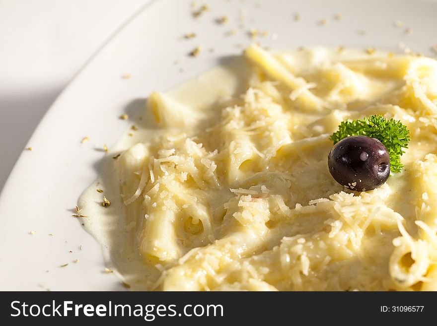 Macaroni with milk soft and cheese decorated with olives.