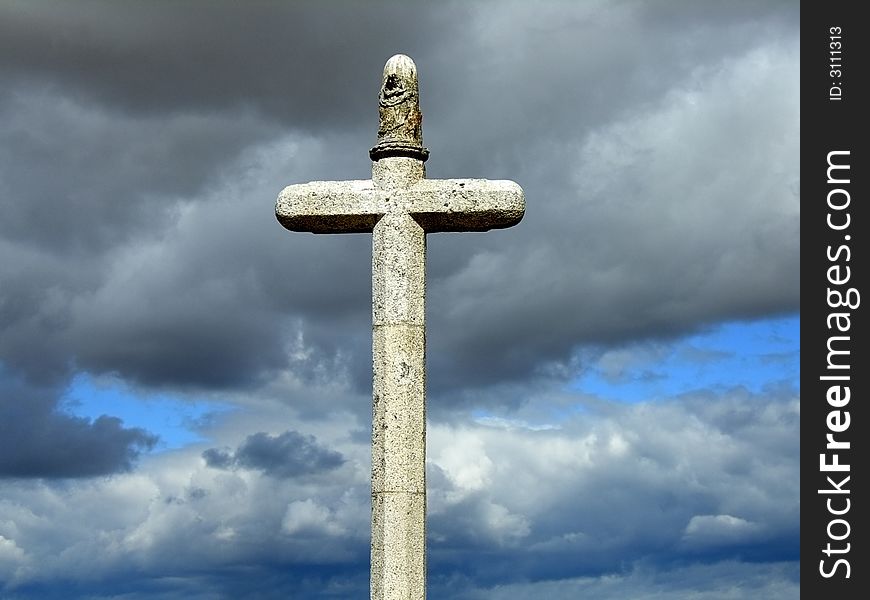 Stone cross with brooding cloudy sky in the background. Stone cross with brooding cloudy sky in the background