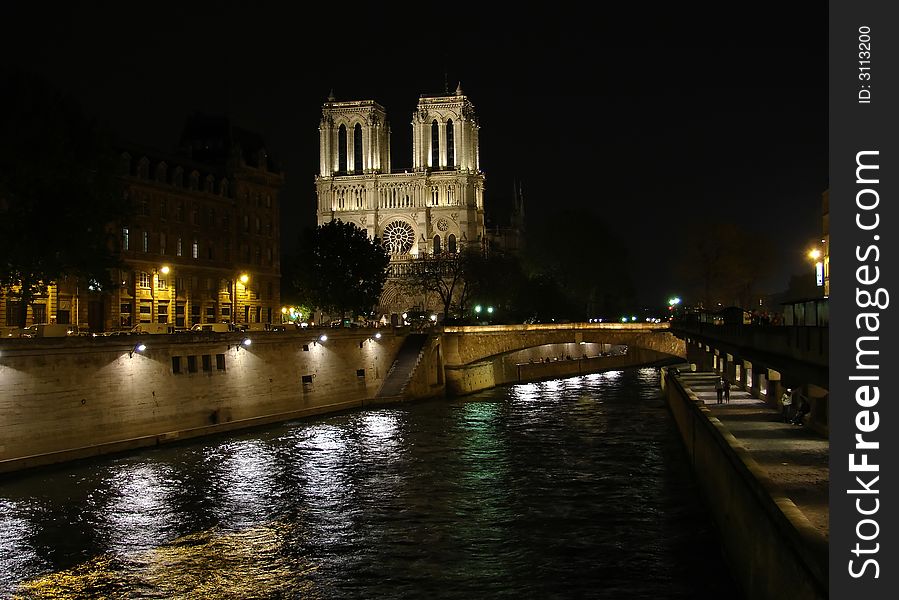 Notre dame de paris at night with the seine river