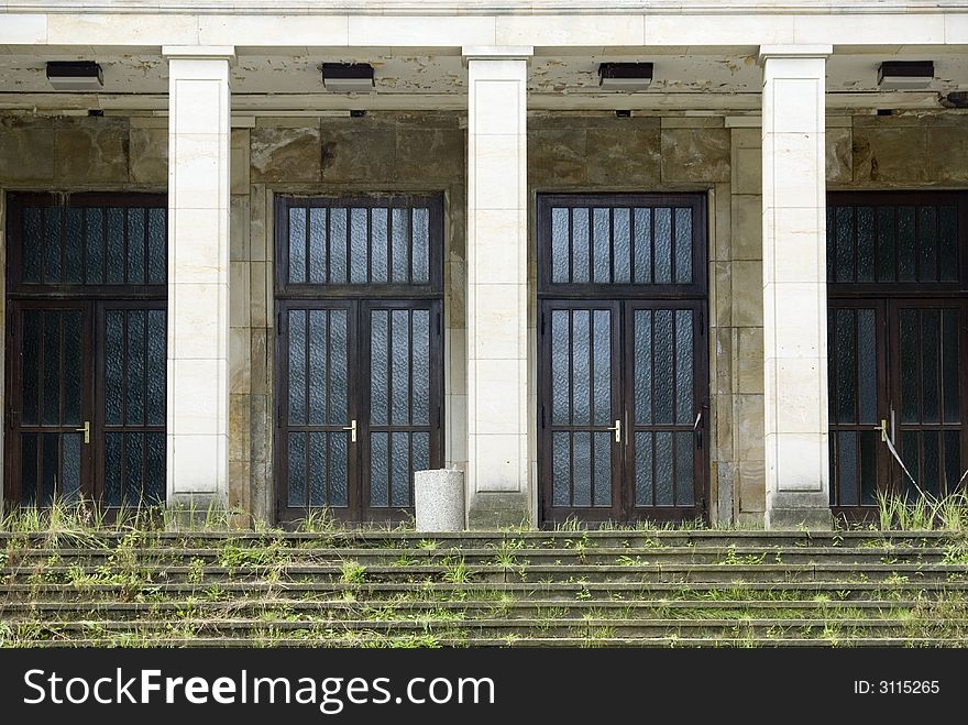 Abandoned hall of the fifities in  Germany, steps covered with weed.