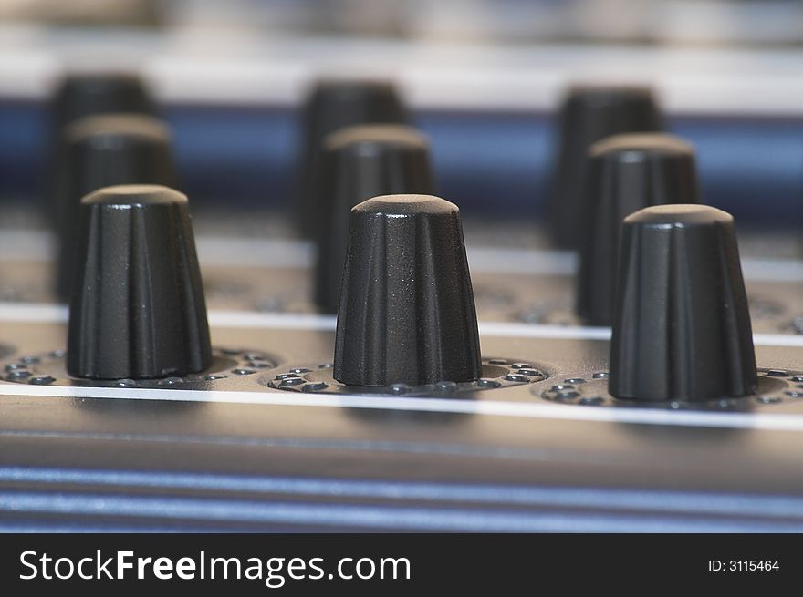 Three rows of midi controller knobs. Shallow depth of field (DOF).