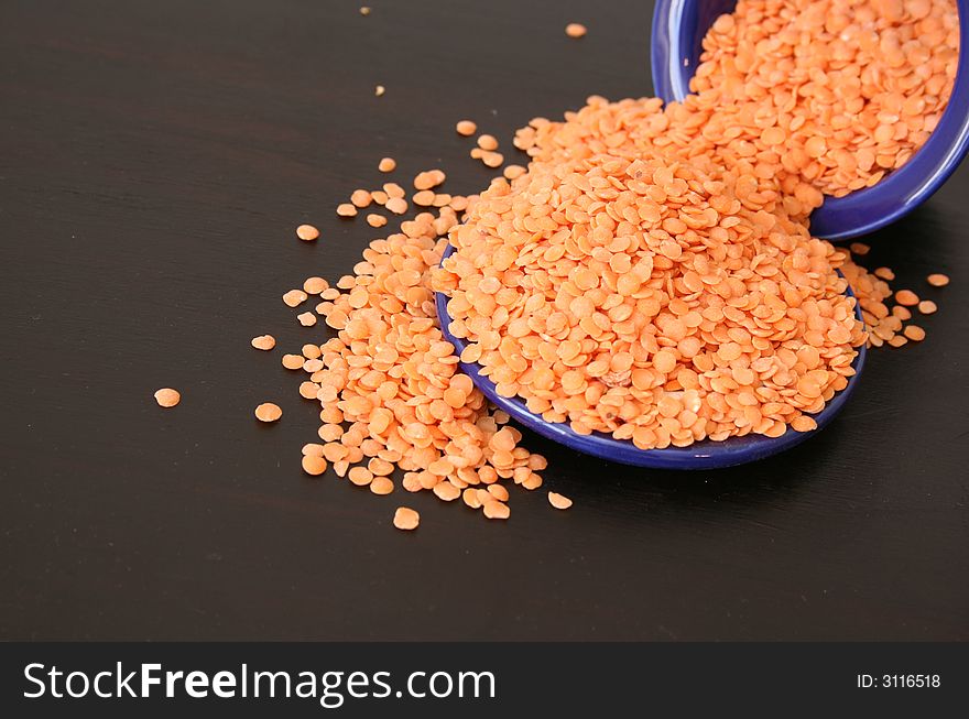 Orange Lentils in a blue container on a brown surface