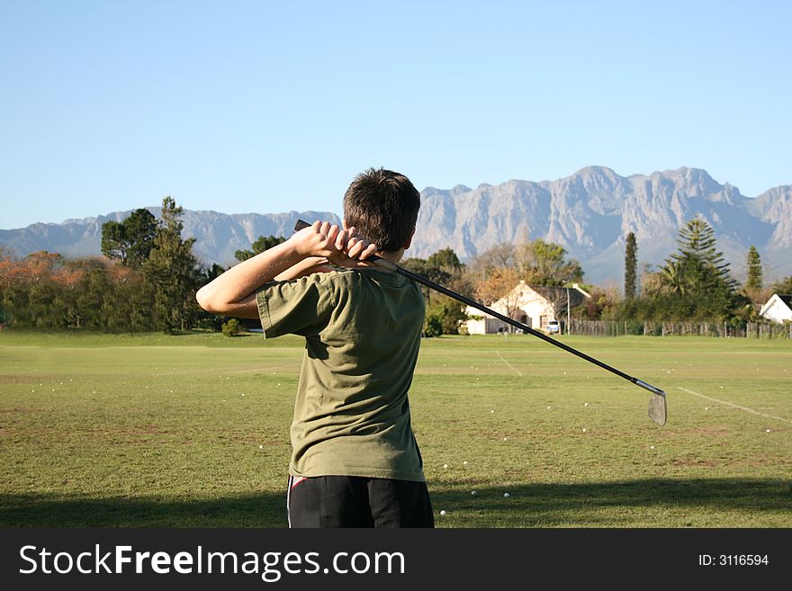 Young golfer practising on the driving range