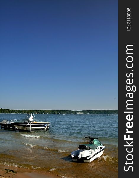 One boat and water scooter at lake shore. One boat and water scooter at lake shore