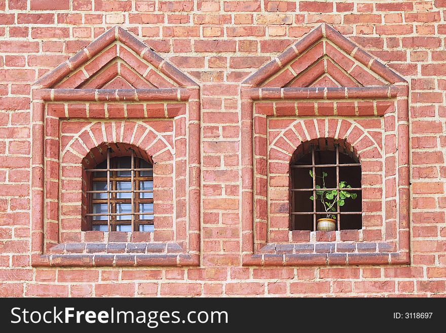 Old windows with bars one of them is opened and there is a green plant. Old windows with bars one of them is opened and there is a green plant