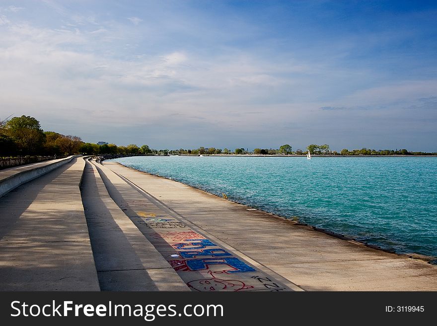 Stepped concrete sidewalk along lake shore with blue water