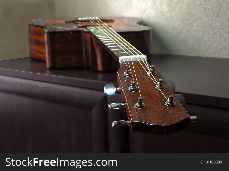 Brown six-string acoustic guitar lying on the table