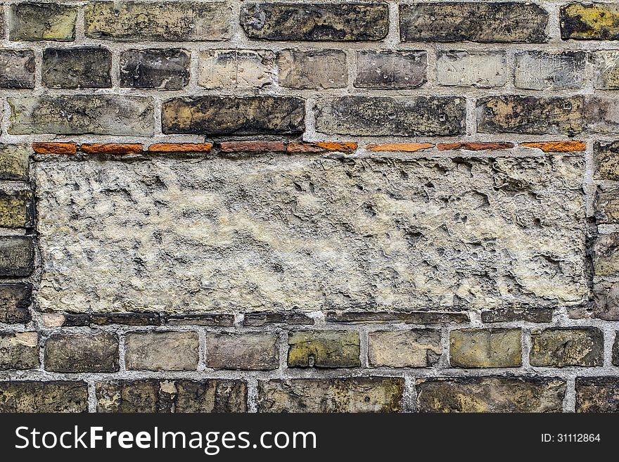 Old brick wall pattern closeup with rectangle of cement in the middle.