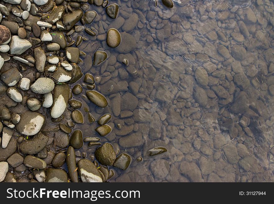 Narrow shore with smooth river stones, and gray water. Narrow shore with smooth river stones, and gray water