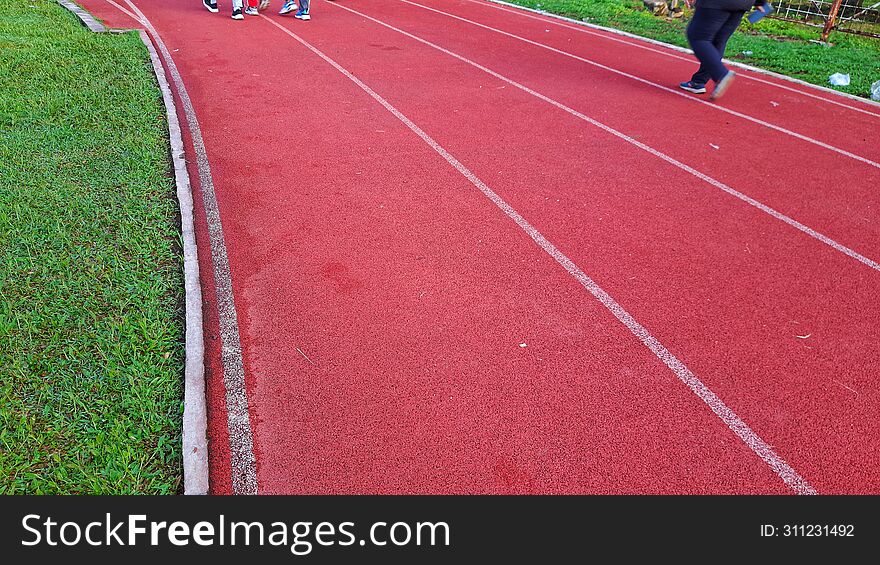 running track in the stadium with a surface suitable for runners& x27  shoes, attractive colors with a combination of white lines, in addition to a well-maintained grass growing path