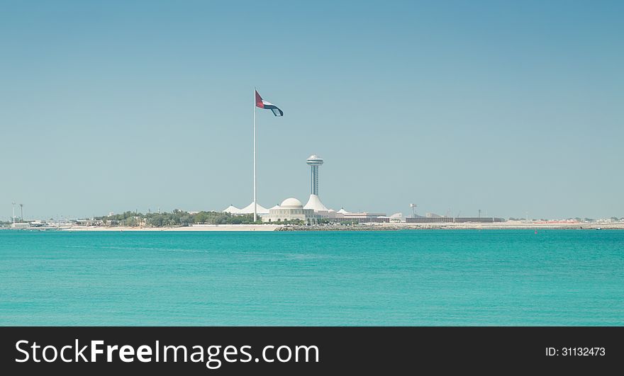 The United Arab Emirates flag, flying next to the Abu Dhabi Heritage Theatre with incredible turquoise water