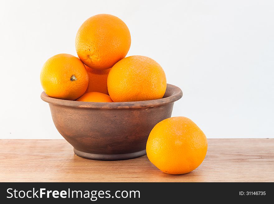 Still life of oranges in a clay bowl