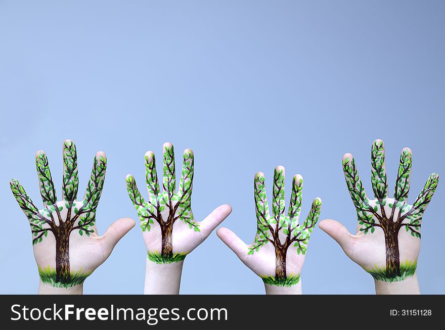 On the raised hands of a child and an adult are painted trees. People protect nature. On the raised hands of a child and an adult are painted trees. People protect nature.