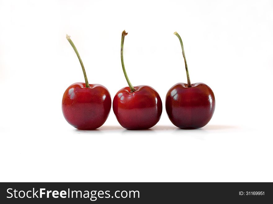 Close up of three cherries on white background