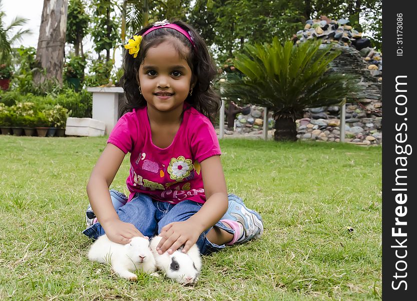 A little girl playing with baby rabbits. A little girl playing with baby rabbits.