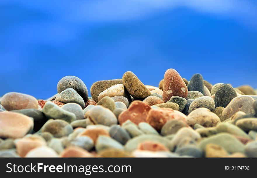 Colorful sea pebbles against the blue of the sea