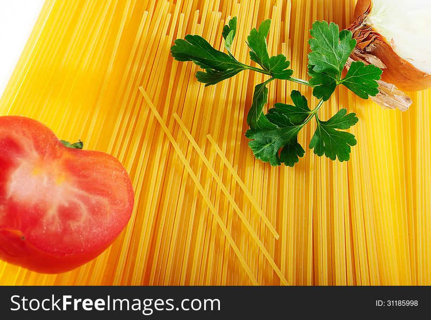 Raw spaghetti decorated with onion, tomato and parsley on white background
