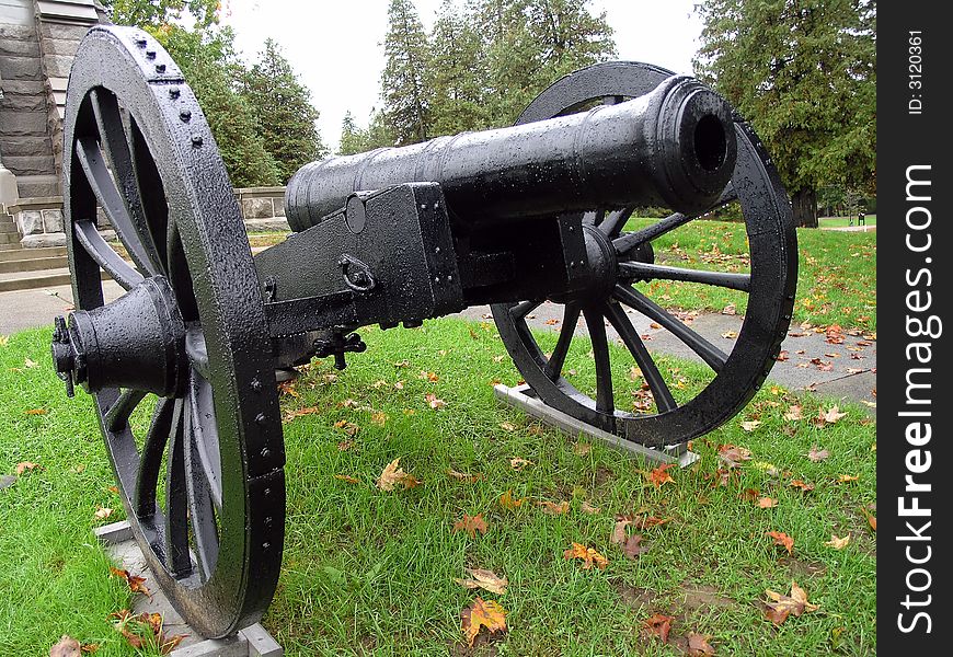 A black cannon guards a monument.