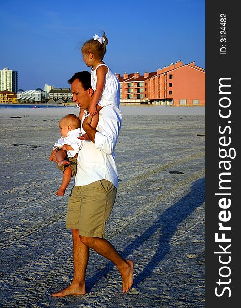 Father walking while holding his daughter and son at the beach. Father walking while holding his daughter and son at the beach