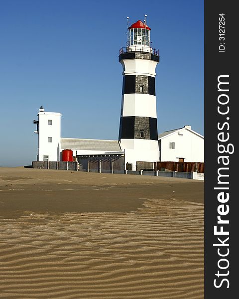 Side view of a lighthouse with sand shapes in the foreground. Side view of a lighthouse with sand shapes in the foreground