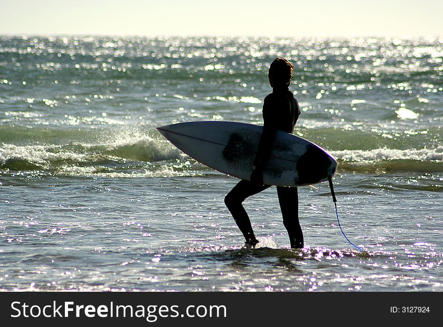 A surfer walking on the shore. A surfer walking on the shore