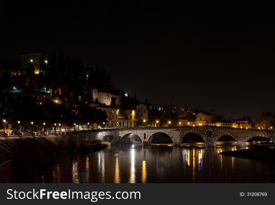 The Adige River that spans the historic center of Verona near the ancient Stone Bridge on a cold winter night. The Adige River that spans the historic center of Verona near the ancient Stone Bridge on a cold winter night.